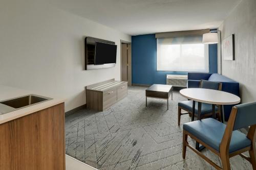 a room with a table and chairs and a tv at Holiday Inn Express Hotel & Suites Branson 76 Central by IHG in Branson