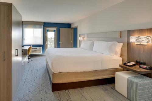 a bedroom with a large white bed and a desk at Holiday Inn Express Hotel & Suites Branson 76 Central by IHG in Branson