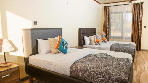 two beds in a room with a window at Matteos Italian Restaurant,Bar & Accommodation in Naivasha