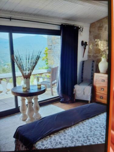 un salon avec une table et une grande fenêtre dans l'établissement La BERGERIE entre mer et montagne, à Bargemon