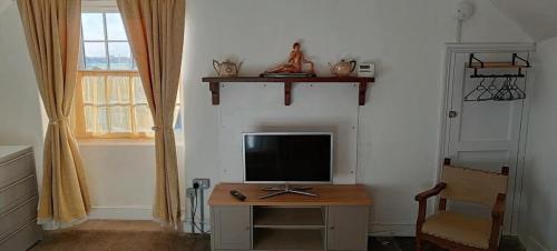 a room with a television on a table with a chair at The Studio Trewarveneth Manor Farm TR185NF in Newlyn