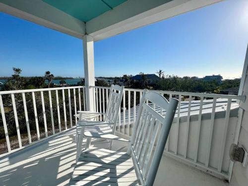 two chairs on a porch with a view of the ocean at Family Tides on LGI - Golf Cart Included in Placida