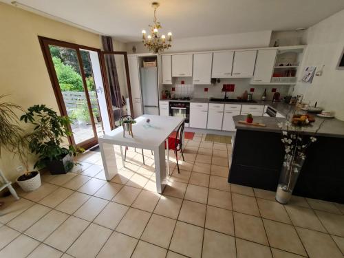une cuisine avec une table blanche au milieu dans l'établissement Maison, grand jardin, lac 8 min à pied, piste cyclable, 6 couchages, à Sévrier