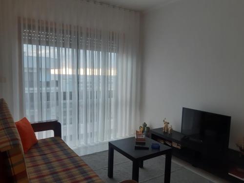 a living room with a television and a couch and a table at Amorosa Beach Sun And Sea in Viana do Castelo