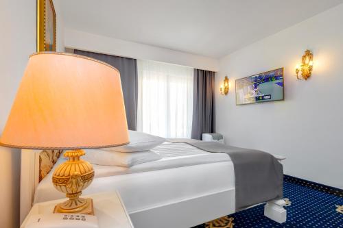 a bedroom with a bed with a lamp on a table at Hotel Imparatul Romanilor Hotel & SPA in Sibiu