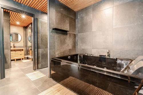 une salle de bain avec baignoire dans une chambre dans l'établissement Villa PAPAGAYO, piscine chauffée, jacuzzi & sauna, à Pessac