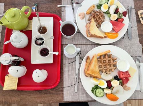 two plates of breakfast food on a table with a red tray at Gite Nycole in Perce