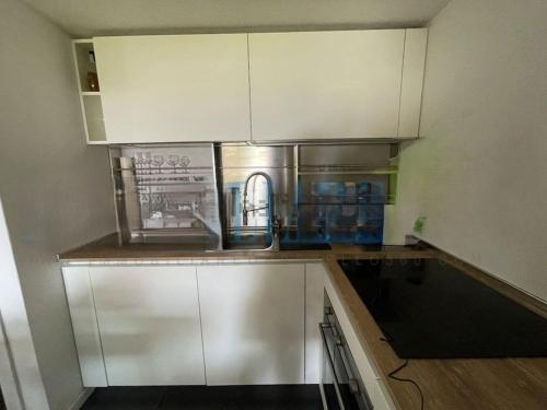 a kitchen with white cabinets and a sink at Villa a schiera Ansedonia in Ansedónia