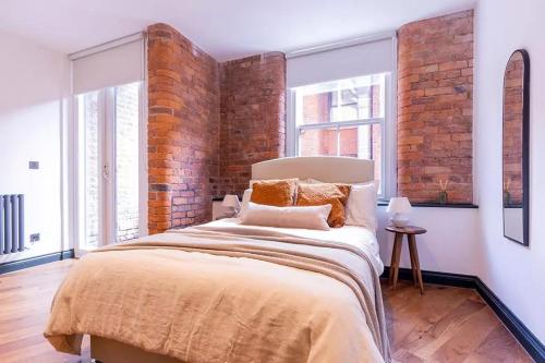 a bedroom with a large bed with a brick wall at 2 bed Luxury Apartment, Parking, Gym, Concierge in Manchester