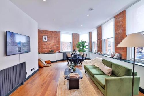 a living room with a green couch and some windows at 2 bed Luxury Apartment, Parking, Gym, Concierge in Manchester