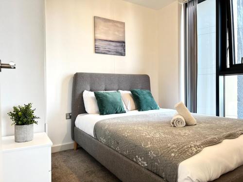 a bedroom with a bed with green and white pillows at Luxury 11th-Floor Penthouse - 2 Bed 1 Bath - City Centre Views - Gym & Netflix in Birmingham