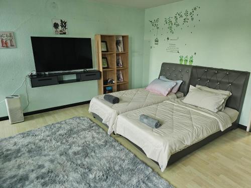 a living room with two beds and a flat screen tv at Arlyn's Homestay in Sandakan