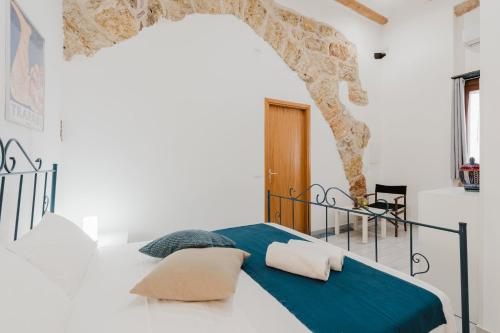 a white bedroom with a bed with a blue blanket at Casa Velella in Castellammare del Golfo