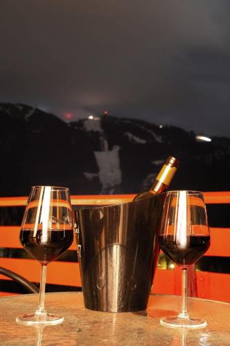 two glasses of wine and a bucket with a bottle of wine at Hotel Piatra Mare in Poiana Brasov
