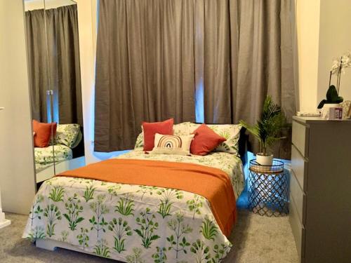 a bedroom with a bed with an orange and white blanket at Amazing Double Ensuite Room in Erith