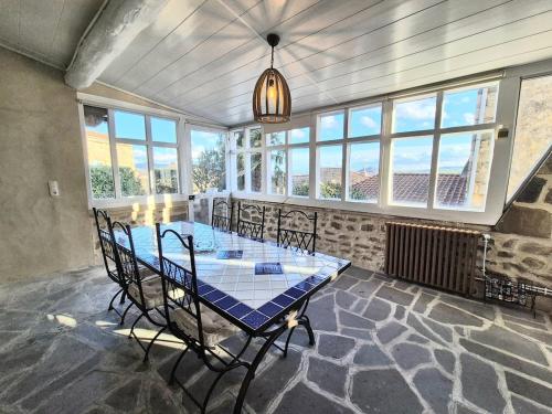 a dining room with a table and chairs and windows at Montpeyruvienne #Jardin#Parking in Montpeyroux