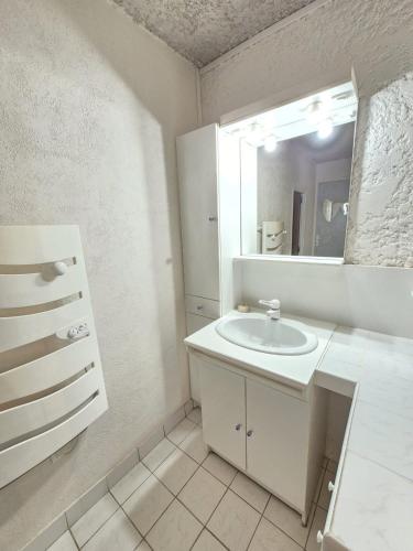 une salle de bain blanche avec un lavabo et un miroir dans l'établissement Montpeyruvienne #Jardin#Parking, à Montpeyroux