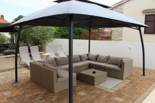 a couch under an umbrella on a patio at Apartments Kimm's Hideaway in Poreč