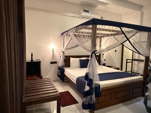 a bedroom with a bed with a canopy at Sea Bay Inn Tangalle in Tangalle