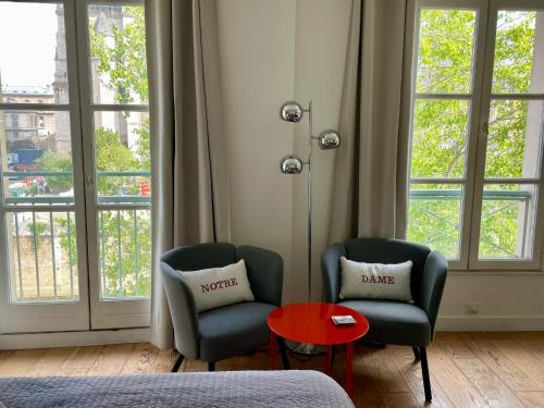 2 chaises et une table dans une chambre avec fenêtres dans l'établissement Le Notre Dame, à Paris