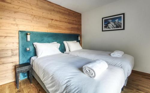 two twin beds in a room with wooden walls at Apartment Aiguille Rose in Les Houches
