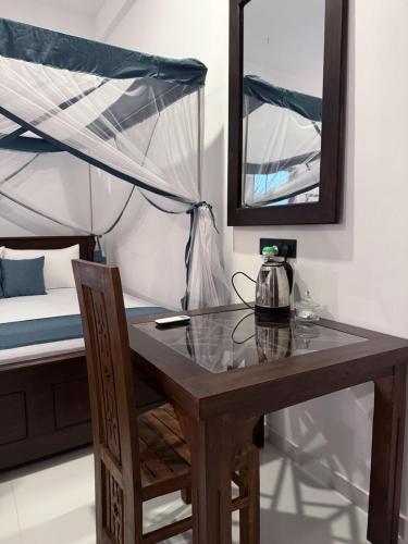 a table and a chair in a room with a bed at Sea Bay Inn Tangalle in Tangalle