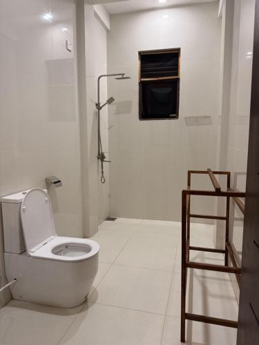 a white bathroom with a toilet and a shower at Sea Bay Inn Tangalle in Tangalle