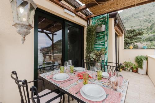 a table with plates and glasses on a balcony at Casa Mauro e Roberta Zingaro in Castellammare del Golfo