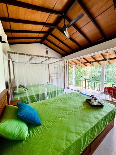 a large green bed in a room with a large window at Rainforest River Bay in Deniyaya