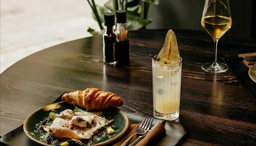 Una mesa con un plato de comida y una copa de vino. en You Boutique Suites, Best Location by BQA, en Budapest