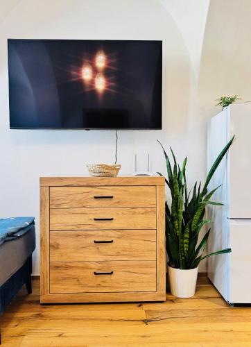 a wooden dresser with a tv on a wall at Apartmán CORA in Jaroměř