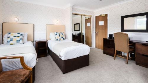 a hotel room with two beds and a desk at Scotland's Spa Hotel in Pitlochry