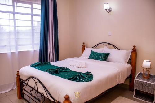 a bedroom with a bed with a green dress on it at The Monarch Suites- Peaceful Luxe 2BR with view in Nakuru
