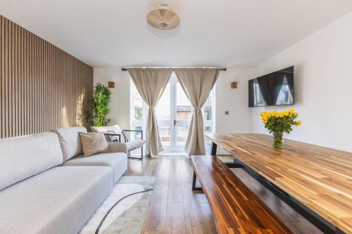 a living room with a white couch and a wooden table at Arte Stays Serviced Houses Stratford - 3 Bedrooms 2 Bathrooms Houses London, Stratford, Maryland, Free Parking, Garden, Weekly or Monthly Stays - up to 8 guests in London