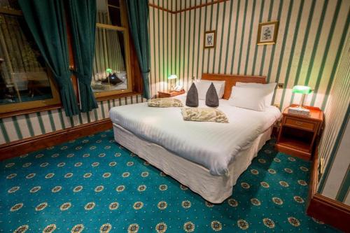 a bedroom with a large white bed with two pillows at Harefield Manor Hotel in Romford
