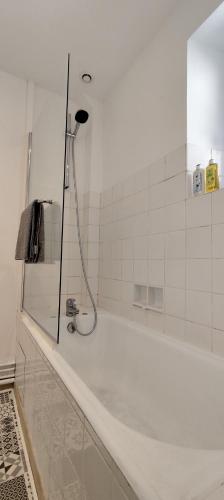 La salle de bains est pourvue d'une douche et d'une baignoire blanche. dans l'établissement Appartement 2 pièces aux pieds de la Cathédrale dans logis du 15ème siècle, au Puy-en-Velay