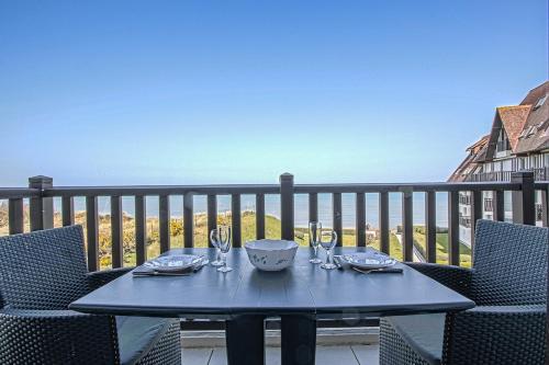 - une table avec des verres à vin sur le balcon dans l'établissement Appartement T2 vue mer, à Cabourg