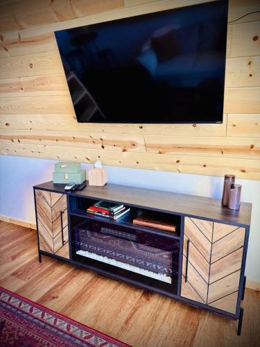 a entertainment center with a flat screen tv on a wall at The Scout a cozy mountain cabin with million dollar view in Ironton