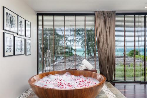 a bathroom with a large wooden tub filled with candy canes at Nikki Beach Resort & Spa Koh Samui in Lipa Noi