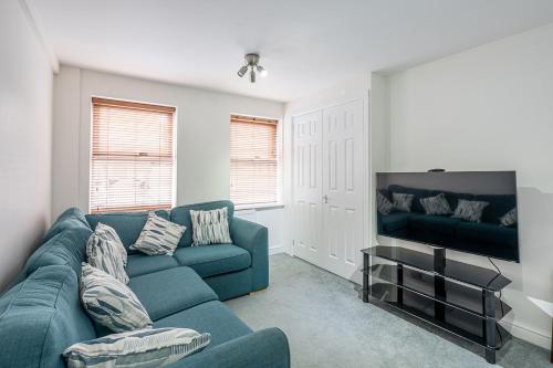 a living room with a blue couch and a tv at Dalesway View in Addingham