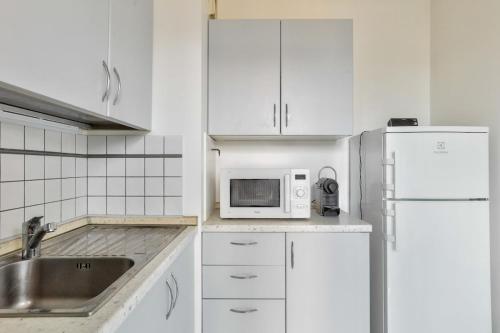 une cuisine blanche avec un évier et un micro-ondes dans l'établissement 1BR Flat with Balcony view of the Eiffel Tower, à Paris