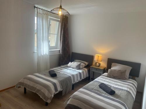 two beds in a small room with a window at Chez Paul in Jeuxey