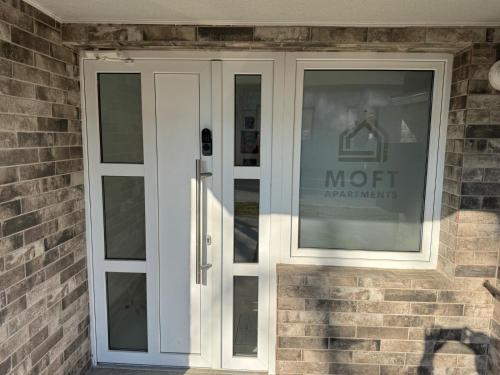 a white door on a brick building with a mopt sign at Moft Hotel Apartments Free Parking Self Check-In in Oradea