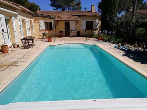 une grande piscine bleue devant une maison dans l'établissement Maison provençale familiale avec piscine - 6 personnes, à Lambesc