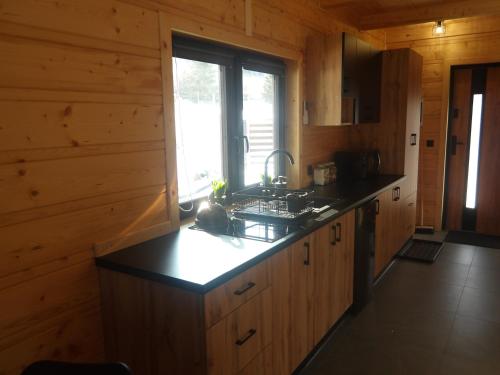 a kitchen with wooden cabinets and a black counter top at Domki na Stodoliskach in Kasinka Mala