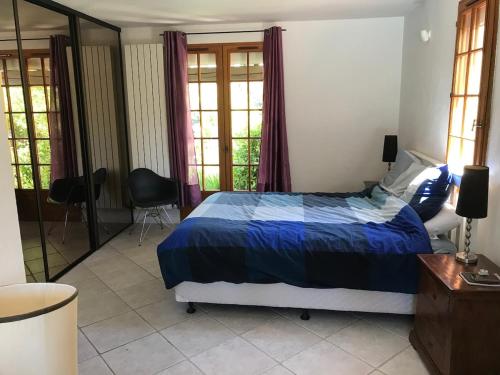 une chambre avec un lit avec une couette bleue et des fenêtres dans l'établissement Maison provençale familiale avec piscine - 6 personnes, à Lambesc