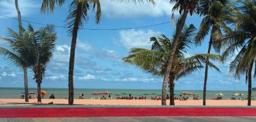 a beach with palm trees and people on the beach at Luxor Tambaú Beach Paradise in João Pessoa
