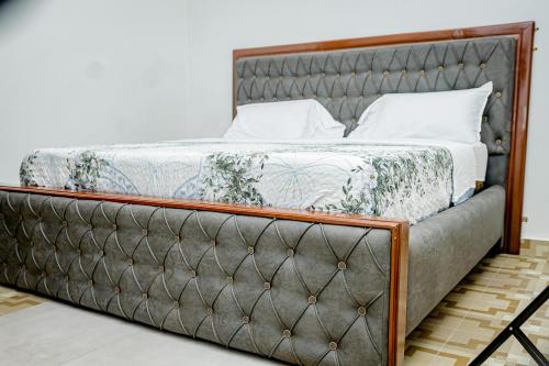 - un lit avec un cadre en métal et des oreillers blancs dans l'établissement Rond Point Gorilla Boutique and Apartments, à Ruhengeri