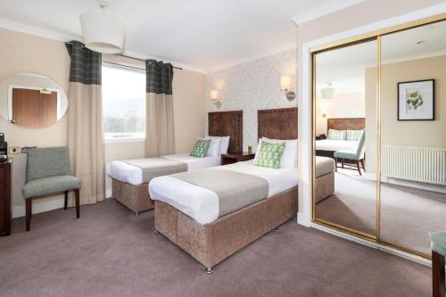 a hotel room with two beds and a chair at Scotland's Spa Hotel in Pitlochry