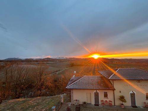 a sunset over a house with the sun setting behind it at La Corte Nascosta Volpedo in Volpedo